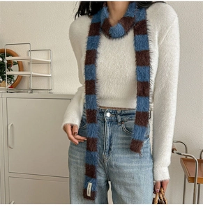 Détail montrant la texture moelleuse et les rayures bleu marron de l'écharpe en peluche
