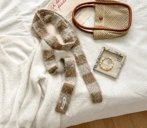 Détail d'une écharpe en peluche à carreaux marron et beige avec étiquette KN STUDIO