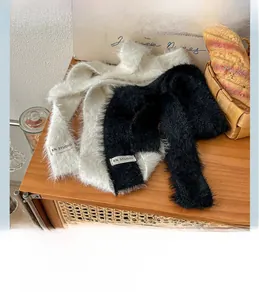 Detail of plush faux fur narrow scarf with KN STUDIO tag on a warm wooden surface