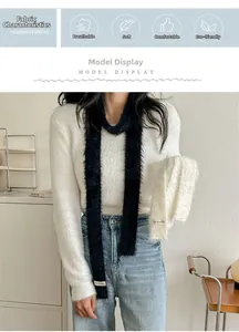 Detail of soft white faux mink scarf with KN STUDIO label on a plush knit sweater