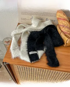 Detailed close-up of soft plush scarves in black and white with minimal fabric labels