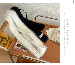 Detailed texture of plush faux fur scarves in black and cream on a wooden table