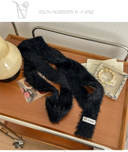 Detail of black plush long scarf showing rich faux mohair texture and a white woven label
