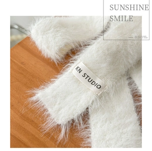 Close-up of white plush scarf showing soft faux fur texture and KN STUDIO woven label