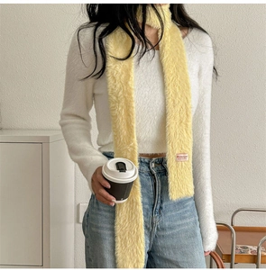 Texture dettagliata di una sciarpa lunga in peluche giallo brillante con etichetta