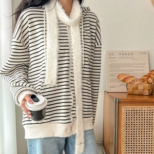 Striped zip-up hoodie paired with a long white plush scarf in a cozy indoor setting