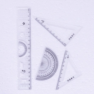 Detailed close-up of a 4-piece clear plastic geometry set with 20cm ruler and scales