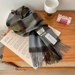 Detail showing the 100% pure wool label and classic plaid fringe of the scarf