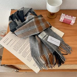 Close-up of 100% pure wool plaid scarf with fringes on a vintage wooden background