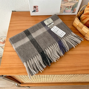 Detail of 100% pure wool checkered scarf with soft fringe on a wooden background