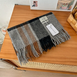 Detail shot of 100% pure wool scarf showing classic plaid texture and tassel edges