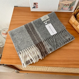 Detail of 100% pure wool scarf with tassel edges and a soft plaid stripe texture