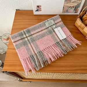 Close-up of pink and grey checkered wool scarf with soft tassels and 100% wool label