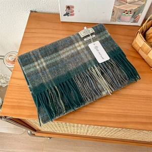 Detail of 100% pure wool scarf featuring classic blue and green plaid with soft fringes