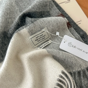 Macro detail of 100% pure wool texture on grey plaid scarf with fringe and quality tags