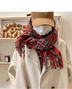 Detailed close-up of a red and blue plaid scarf with long tassels in a cozy bakery setting