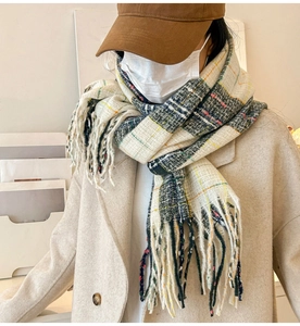 Detail showing checkered scarf with fringe tassels paired with a wool coat and brown cap