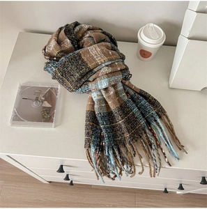 Macro view of multi-colored retro plaid scarf with tassel details on a white cabinet