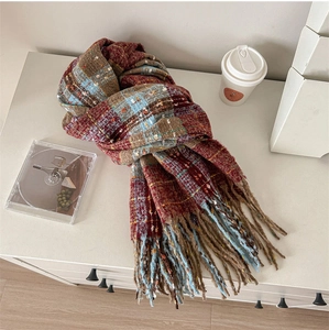 Detail of classic red and blue plaid knit scarf with long tassels on a cozy white desk