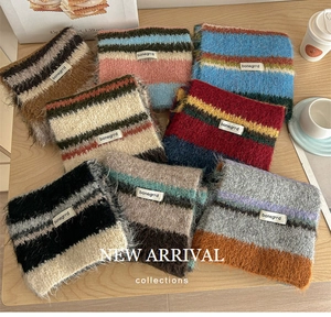 Detail of colorful striped mohair wool scarves with brand labels on a wooden surface