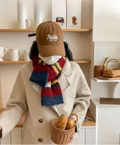 Detail of colorful striped wool scarf paired with a brown Malibu hat and oatmeal coat