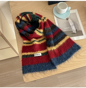 Flat lay of a striped wool knit scarf with a bonegrrd label on a wooden desk with a coffee cup