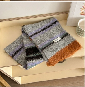 Detailed view of colorful striped wool knit scarf with soft plush texture on wooden shelf