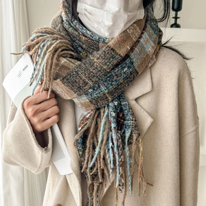 Plaid tassel scarf in brown and blue tones paired with a beige coat for winter warmth