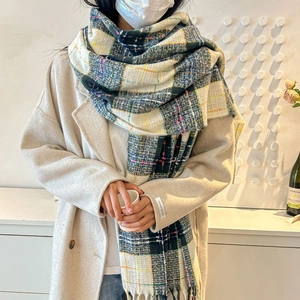 Classic checkered wool scarf with fringes in green and white, paired with beige coat