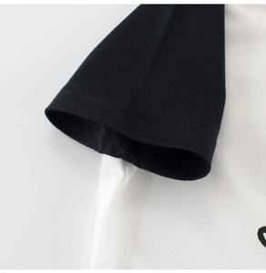 Detail view of double-stitched sleeve cuff on kids' cotton black and white raglan T-shirt