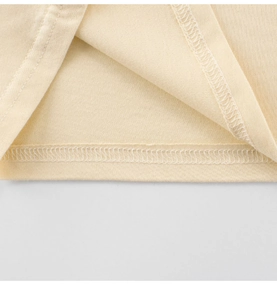 Détail du point double aiguille sur l'ourlet d'un t-shirt en coton crème pour enfants