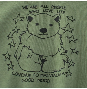 Close-up of green cotton kid's T-shirt featuring hand-drawn bear and inspirational text