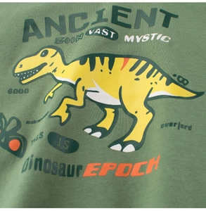 Détail de l'imprimé dinosaure jaune sur le tissu en coton vert d'un t-shirt garçon