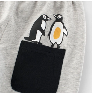 Detail of gray knit boys' shorts featuring a black pocket with cute penguin prints