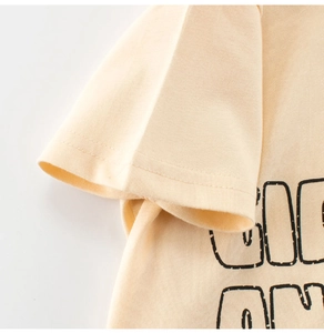Detailed close-up of soft cotton beige fabric and black letter print on boy's T-shirt