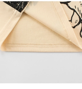 Close-up of double-needle stitching and dinosaur print on beige cotton t-shirt hem