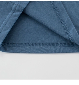 Gros plan d'un t-shirt bleu en coton montrant les coutures renforcées sur le bord
