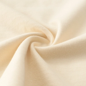 Macro shot of soft cream knit cotton fabric showing fine texture and premium quality