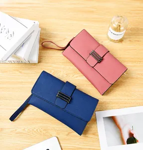 Détail de pochettes en cuir grainé rose et bleu marine avec dragonnes sur table en bois