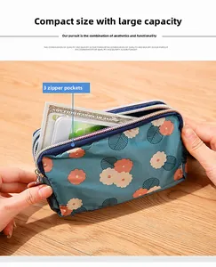 Primer plano de un mini bolso de lona floral con tres cremalleras para móvil y billetes