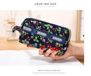 Détail d'un porte-monnaie en toile bleu marine avec imprimé fraises et double fermeture éclair