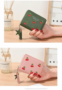 Close-up of cherry embroidered short wallets in green and pink with star tassel zipper