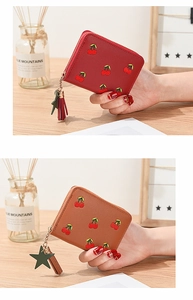 Close-up of short litchi leather wallet with cherry embroidery and star tassel pendant