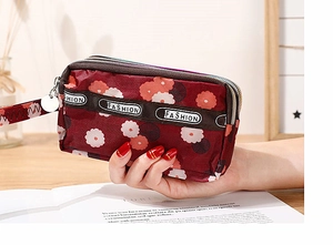 Détail d'un porte-monnaie en nylon bordeaux à fleurs avec trois fermetures éclair