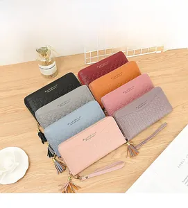 Flat lay of multiple colorful leather long wallets with tassel charms on a wooden surface