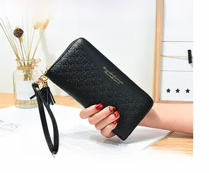 Close-up of black long leather wallet with embossed pattern and gold tassel zipper