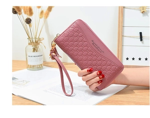 Close-up of pink leather wallet with circle embossed pattern and tassel accessory