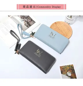 Detail of light blue and dark grey zip wallets with butterfly gold hardware and tassels