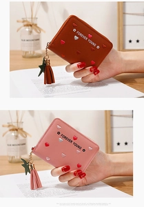 Close-up of heart embroidery and tassel star charm on faux leather long zipper wallet