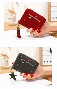 Detail of zip wallets in red and grey lychee leather with heart embroidery and tassels
